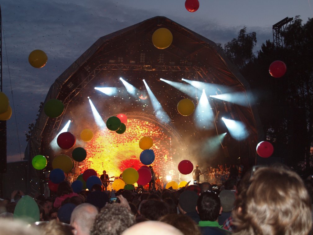 Brightly coloured balloons floating in front of a brightly lit stage